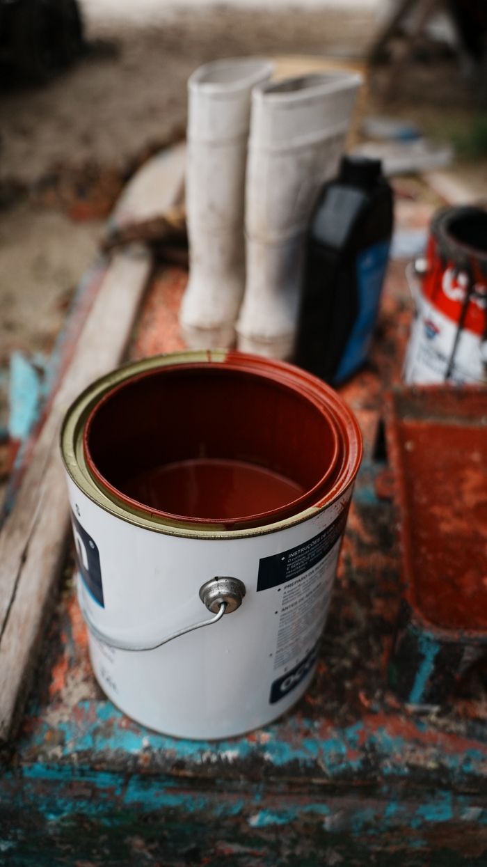Close-up of paint cans and boots on a dock, capturing the essence of artisanal fishing maintenance.