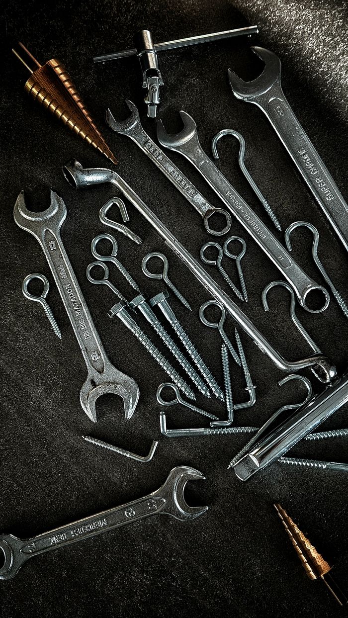 A collection of vintage hand tools including wrenches and screws on a dark surface.